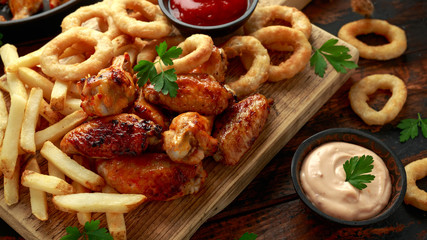 Fried Chicken wings with onion rings, french fries and dipping sauce. take away food.