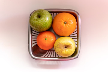 Basket full of fruits: apples, oranges and clementines in a grey background. Top view