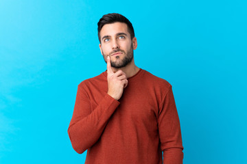 Young handsome man with beard over isolated blue background thinking an idea