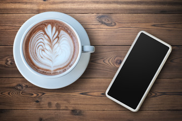 Smartphone with a cup of Espresso coffee with beautiful latte art on wooden background.