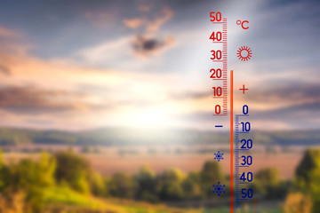 The thermometer on the background of the summer landscape shows 25 degrees above zero_