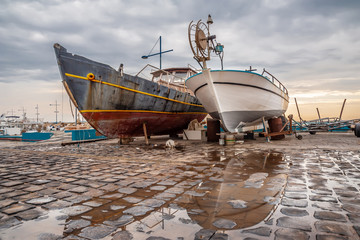 Two ships stand on land in port