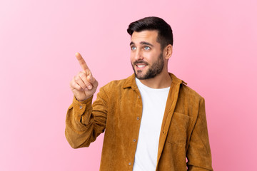 Young handsome man with beard wearing a corduroy jacket over pink background touching on transparent screen