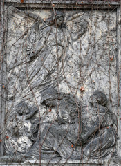A weathered, nearly overgrown sandstone sculpture of a resting angel on a tomb of a cemetery in Berlin-Germany.