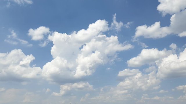 Blue summer sky with dense thick thunderstorm rain clouds moving across the heavens. Fast cloud formation and movement creating a surreal time lapse.