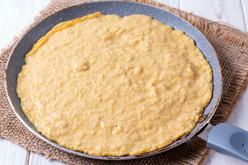 Frying pan with raw dough. Cooking pancakes