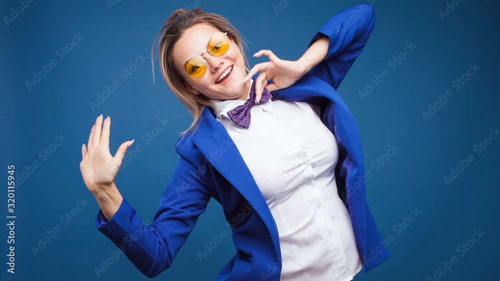 Wall mural jumping and dancing businesswoman in stylish blue jacket and bow tie. Portrait of a cheerful girl