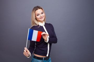 Immigration and the study of foreign languages, concept. A young smiling woman with a France flag in her hand.