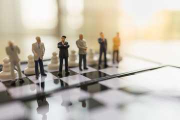 Business, Teamwork and Planning Concept.  Close up of businessman miniature people figure standing on chessboard with pawn chess pieces and copy space.