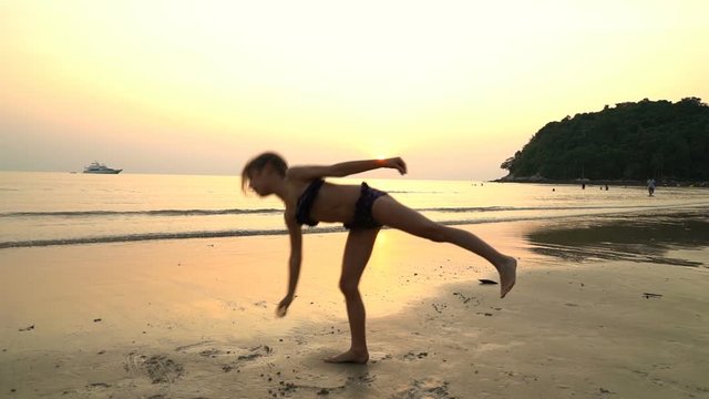 little girl doing gymnastics on beach sunset sea.
