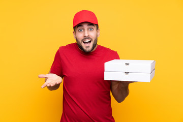 pizza delivery man with work uniform picking up pizza boxes over isolated yellow background with...
