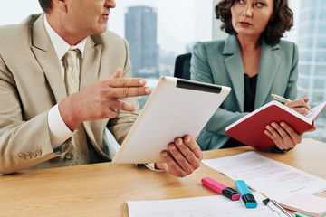 Obraz premium Middle-aged Caucasian business people working together sitting at office desk, horizontal shot