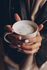a cup of fragrant morning coffee before work or school. Photo of the female hands  holding a cup with pictures of little hearts. Ideal for advertising or banner