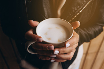 a cup of fragrant morning coffee before work or school. Photo of the female hands  holding a cup with pictures of little hearts. Ideal for advertising or banner