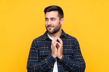 Young handsome man with beard over isolated yellow background scheming something