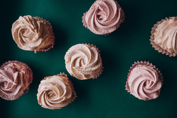 pink muffins with cream on a dark green background
