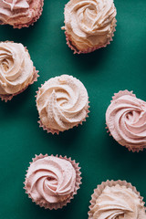 pink muffins with cream on a dark green background