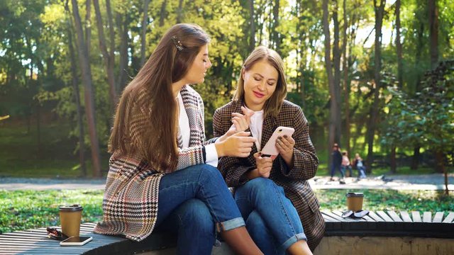 Fashionable girls watching photos in social media using smartphone in park