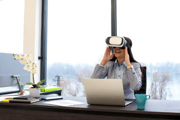 Businesswoman wearing virtual reality googles, VR headset, attending virtual  business meeting