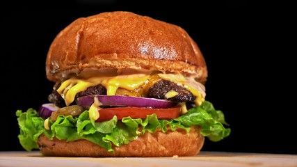 Craft burger is cooking on black background. Consist: sauce, lettuce, tomato, red onion, pickle,...