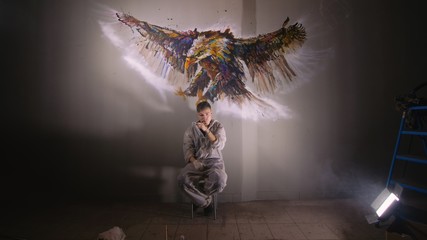 Artist designer draws an eagle on the wall. Craftsman decorator paints a picture with acrylic oil...