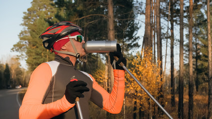 Training an athlete on the roller skaters. Biathlon ride on the roller skis with ski poles, in the...