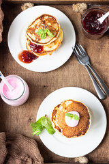 Wooden tray with pancakes, red berry jam, yogurt and mint. Perfect breakfast. American cuisine.