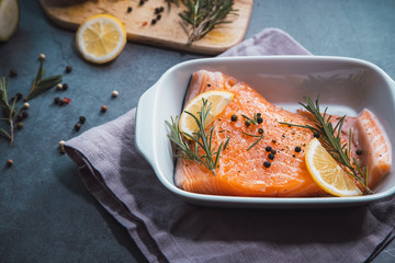 Fresh salmon fillet with lemon slices, rosemary and pepper.
