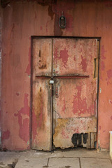a whole old wretched door with a lock. The door of a house owned by poor, impoverished residents.
