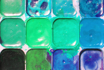 Bright blue, black and green colors mixed in a plastic box. dusty and dirty watercolor. drawing concept. Original creative background