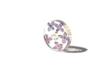 Beautiful violet button isolated on white background situated top right. Lilac flower in epoxy resin, suitable for text insert.