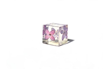Beautiful simple violet and white background suitable for text input. Handmade epoxy resin cube with lilac flower, isolated on white background.