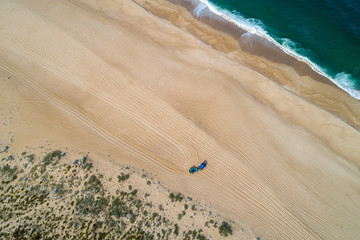 A blue tractor prepares the sand of Praia do Norte in Nazaré, early in the morning. Portugal.