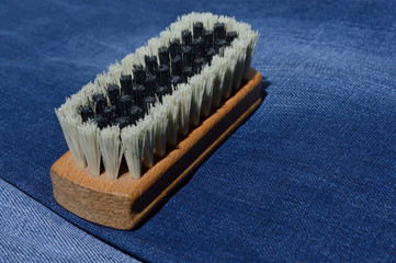 a clothes brush lies on folded jeans.