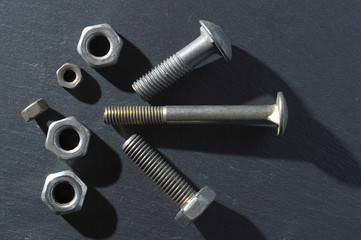 old bolts and nuts on a dark background. Top view.