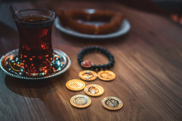 Set up on wooden table: turkish black tea with a bracelet  with national flag nearby and six (6) currency coins of 1 lira. Blank space. Background image.