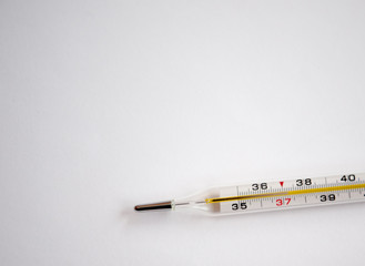 Mercury thermometer with temperature and a handful of yellow tablets on a light background. The...