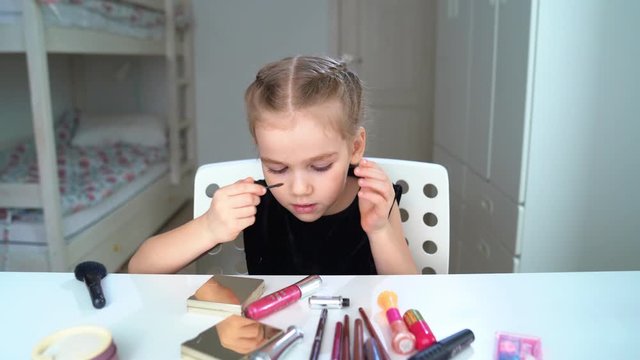 Little girl doing the makeup at home. Beauty blogger. Paint the eyebrows.