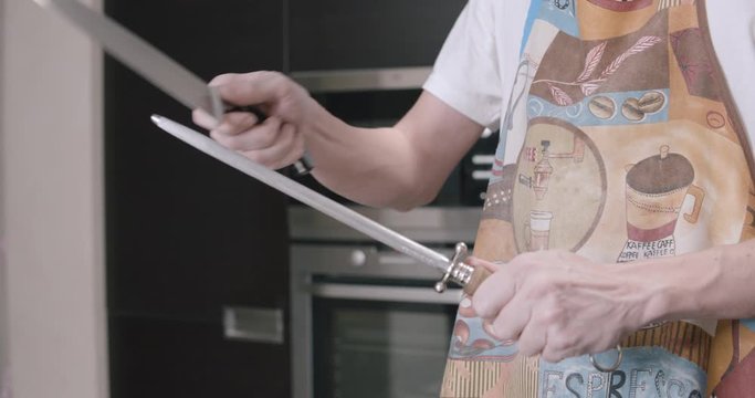 Knife sharpening by chef in the home interior at the kitchen