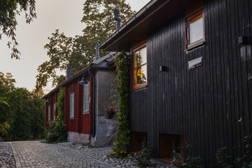 Coblestone street and traditional Swedish wooden houses shot in the evening, with warm yellow light streaming from the windows