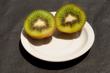  image of kiwi in a white plate on a black background