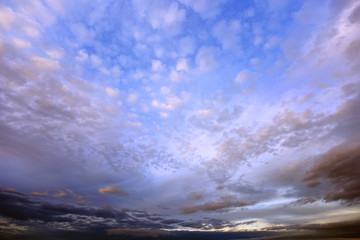 Burzowe chmury na błękitnym niebie w czasie zachodu słońca.	