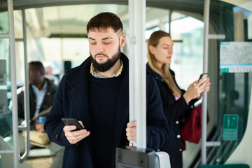 Fototapeta na wymiar Young man with phone in city tram