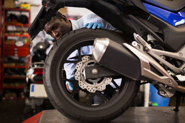 Afro american expert inspects the wheel of a motorcycle