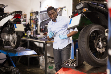 Afro american expert inspects the wheel of a motorcycle