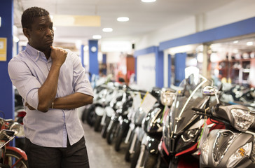 Portrait of adult man buying new motorcycle at modern showroom