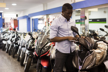 Portrait of adult man buying new motorcycle at modern showroom