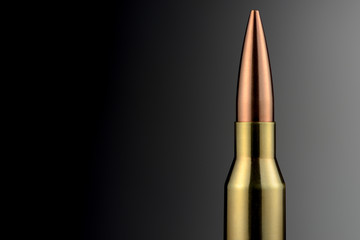 A 338 Lapua Magnum rifle cartridge in front of a gray gradient as a close-up. Brass and copper...