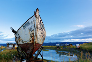 Derelict boats bathed in golden sun lights at Homer Spit, Alaska at sunrise. Homer is a small city...