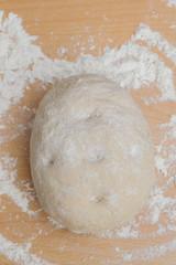 Prepared kneaded dough on a wooden table at home